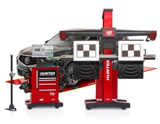 Professional ADAS (Advanced Driver Assistance Systems) calibration equipment by Hunter Engineering Company set up in front of a dark-colored SUV. The equipment includes a red mobile tool cabinet with a computer monitor displaying diagnostic software, and a large red calibration fixture with high-contrast checkerboard targets and integrated sensors used for aligning vehicle safety systems.