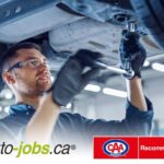 Un mécanicien portant des lunettes de sécurité et des gants travaille sous un véhicule avec une clé à douille, accompagné des logos de Auto-jobs.ca et de CAA-Québec Recommandé au bas de l'image.