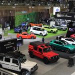 Vue en plongée de l'aire d'exposition du Salon international de l’auto du Canada 2026, montrant une grande variété de véhicules colorés et de kiosques de constructeurs.