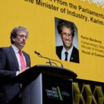 Karim Bardeesy, secrétaire parlementaire du ministre de l'Industrie, prononce un discours au podium lors de l'EV & Charging Expo 2026. Il se tient devant un grand écran jaune qui affiche son portrait, son nom et ses titres officiels auprès de la Chambre des communes du Canada. Le podium porte le logo de l'événement « EV & Charging Expo 2026 ». Lors de cette allocution, M. Bardeesy a annoncé un investissement fédéral de 10,6 millions de dollars pour financer 14 projets d'infrastructure de recharge de véhicules électriques à travers le pays.