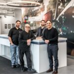 Max, Otto, Mike, and Albert Rosanova standing behind the modern reception desk at Fix Auto Edmonton West.
