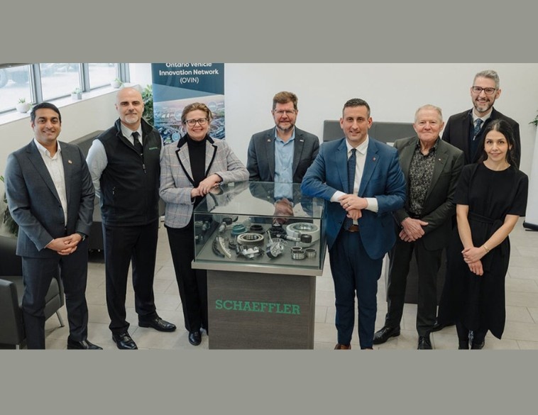 Eight professionals from the Ontario Vehicle Innovation Network (OVIN) and Schaeffler stand around a display case of mechanical components to mark their strategic partnership.