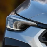 A close-up of a modern silver car's front headlight assembly and hood, showcasing the intricate and complex design of contemporary automotive lighting.
