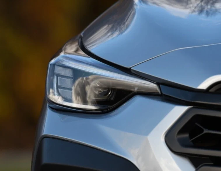 A close-up of a modern silver car's front headlight assembly and hood, showcasing the intricate and complex design of contemporary automotive lighting.
