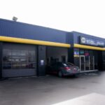 Extérieur de l'établissement de services automobiles NAPA AUTOPRO Upper James, arborant l'image de marque bleue et jaune et les baies de service.