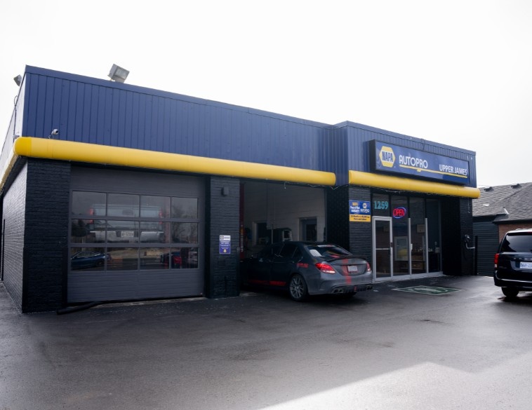 Extérieur de l'établissement de services automobiles NAPA AUTOPRO Upper James, arborant l'image de marque bleue et jaune et les baies de service.