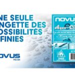 Une publicité pour NOVUS Polish présentant la lingette hydrofuge AquaClear. À gauche, le slogan en majuscules bleues indique « UNE SEULE LINGETTE DES POSSIBILITÉS INFINIES ». À droite, l'emballage du produit affiche des icônes de pare-brise et de douche sur un fond parsemé de gouttelettes d'eau.