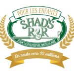 Logo de l'événement caritatif Shad’s R&R avec des éléments dorés et verts. Une bannière supérieure indique « POUR LES ENFANTS ». Un grand ovale vert encadre « SHAD’S R&R » avec un bâton de golf et l'inscription « POUR LA DYSTROPHIE MUSCULAIRE ». Des épis de blé dorés encadrent les côtés, et une bannière inférieure affiche « En route vers 10 millions ».