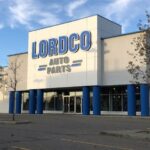 Vue extérieure d’un magasin Lordco Auto Parts montrant la façade blanche et bleue avec sa grande enseigne sous un ciel dégagé.