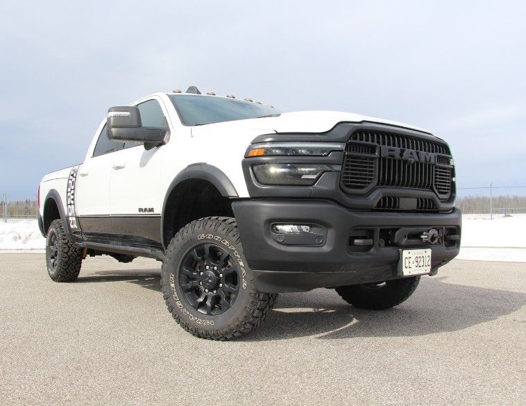 Low-angle front view of a white 2026 RAM 2500 Power Wagon with black grille, off-road tires, and lower body blackout graphics.