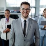 Équipe de gestionnaires souriants en salle de montre, illustrant le leadership en concession automobile.
